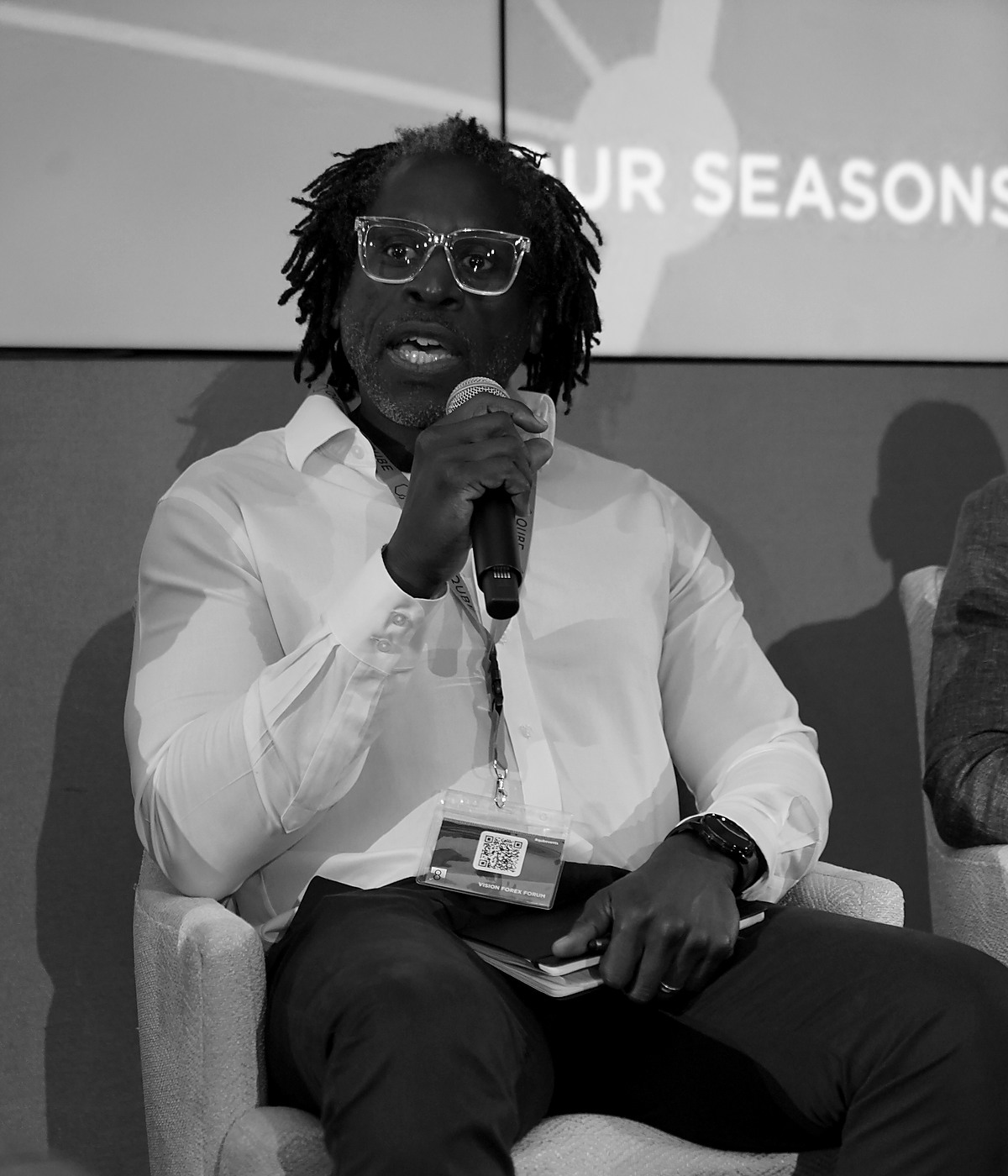 Uchenna Oranu speaking into a microphone at a professional forum