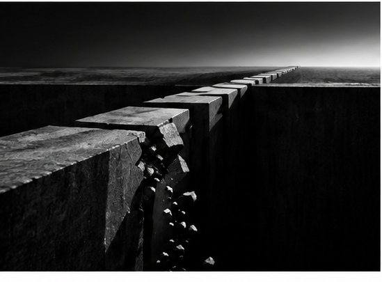 A fractured sequence of stone blocks crossing a dark divide